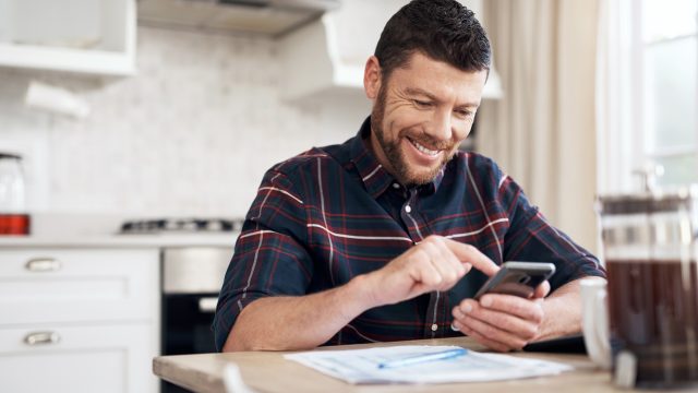 A man sitting at his counter using a calculator to file his taxes