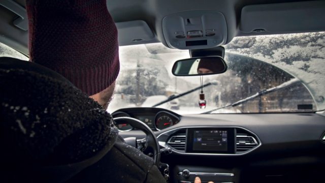 Man driving car in snowy winter outdoors