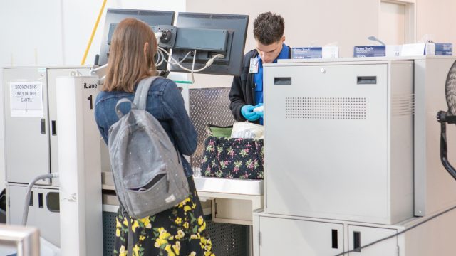 A TSA agent searching a woman's bag at the airport