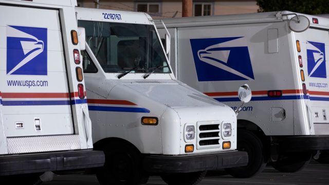 USPS (United States Parcel Service) mail delivery trucks sit parked for the night.