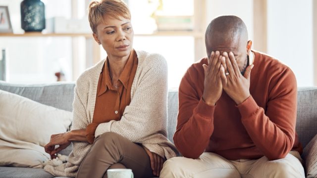 annoyed wife looking at her husband sitting on the cough