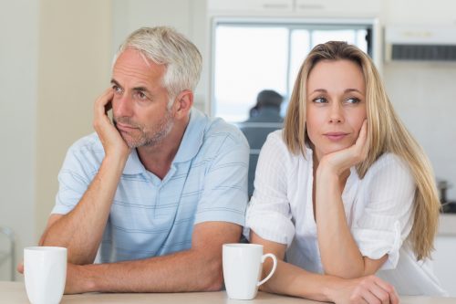 Bored couple sitting at the counter at home in the kitchen