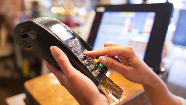 A close-up of someone using a debit or credit card terminal to make a payment