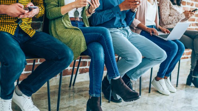 Group of people sitting in a row all wearing jeans