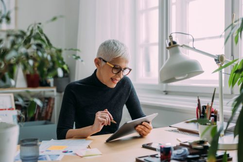 A happy charming Caucasian grey woman being focused on her work in black turtle neck sweater
