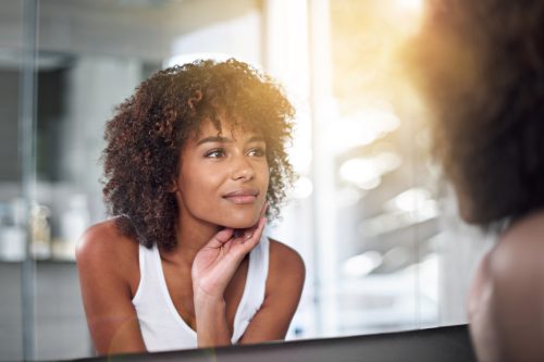 Woman looking at her skin in the mirror.