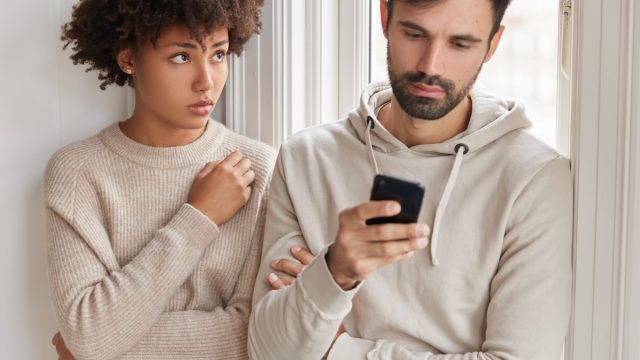 A man looking at his phone and ignoring the woman next to him.