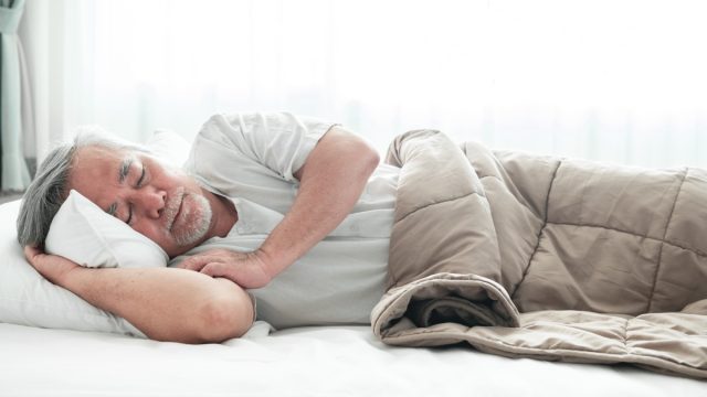 Older asian man sleeping comfortably in bed with curtain open