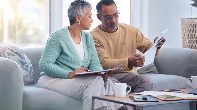A middle-aged couple on their couch going over bills.