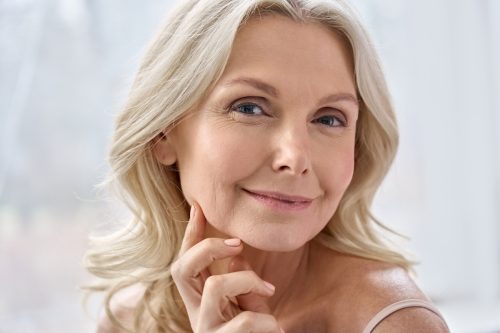 Smiling older blonde woman touching face