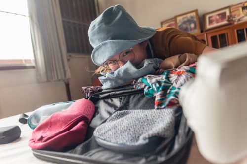Woman Smelling Clothes in Suitcase