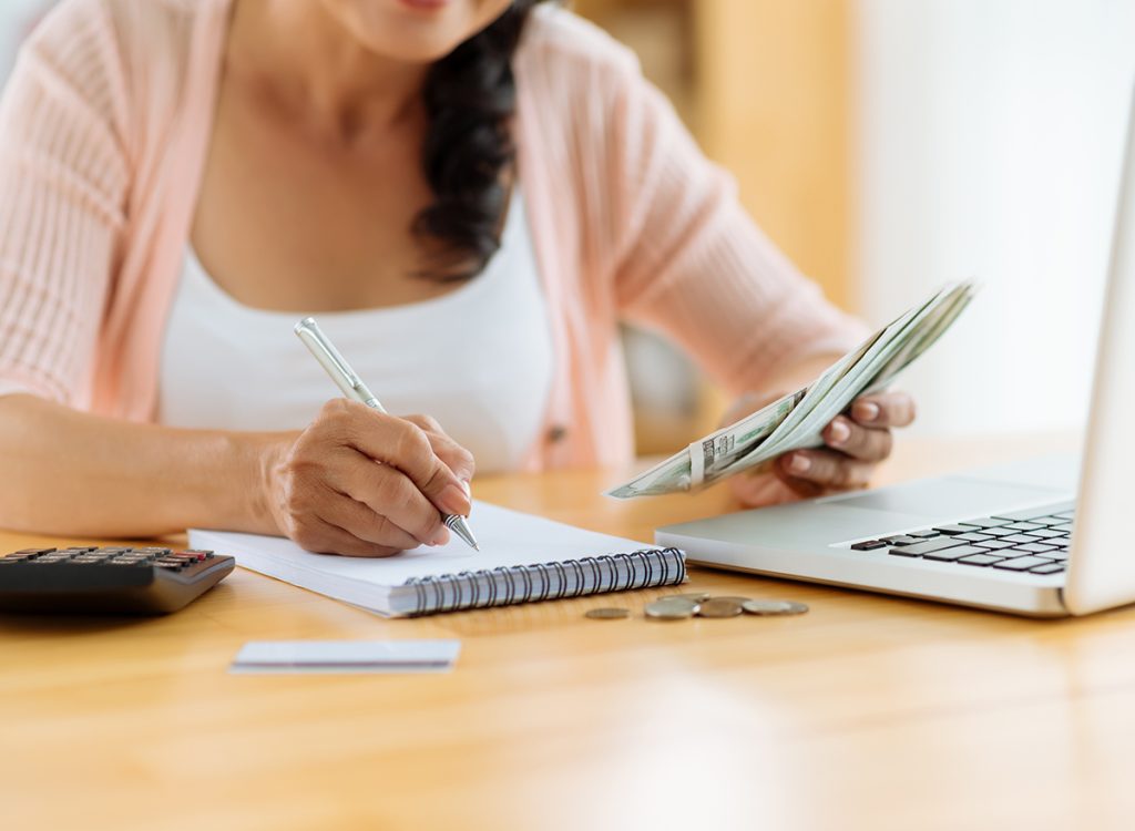 A person going over their budget using a laptop and pad of paper
