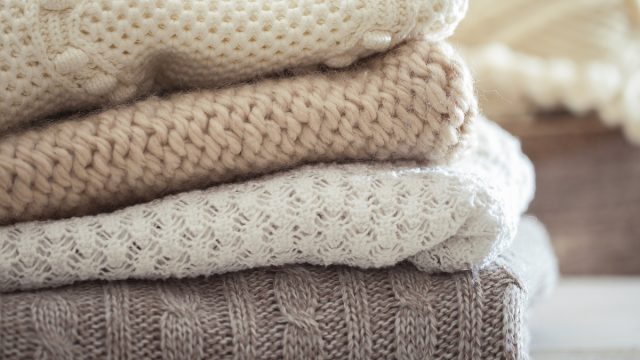 Stack,Of,Cozy,Knitted,Sweaters,On,A,Wooden,Table.,Retro
