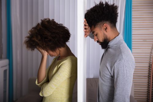 Unhappy couple standing by the door in silence.