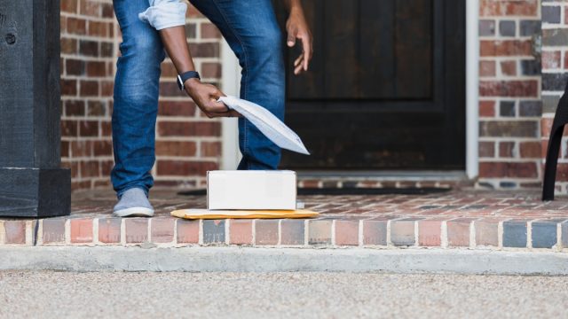 Unrecognizable man picks up packages on doorstep