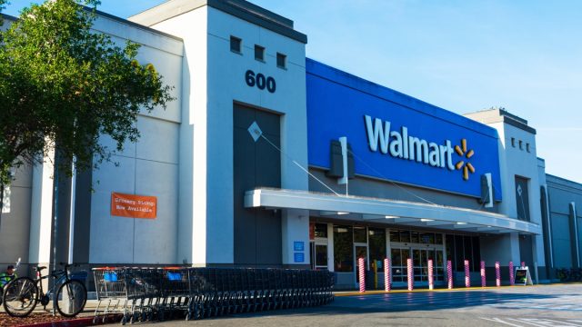 Walmart store facade. Row of shopping carts are ready for customers. Anti ram raiding bollards secure Wal-mart entrance from accident or theft
