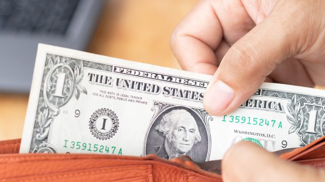 A hand pulling a one dollar bill out of a wallet