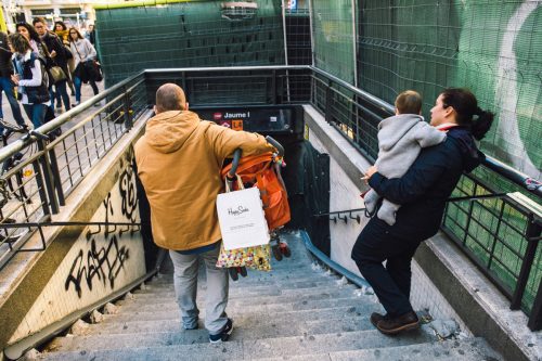man carrying a stroller down the subway stairs as a random act of kindness