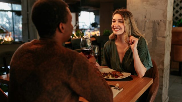 A young happy woman is in a restaurant on a Valentines date with her boyfriend.