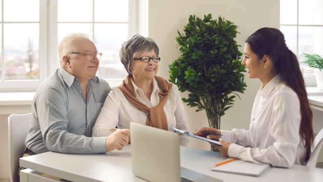 Two retirees talk to a tax consultant in a well lit room.