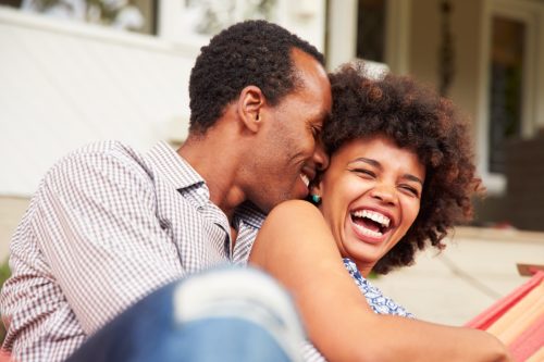 man and woman cuddling and laughing on the couch