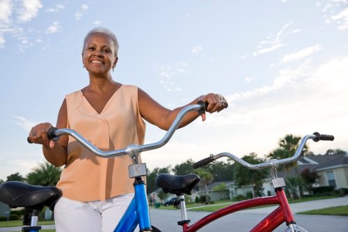 senior woman in pale orange top with bike