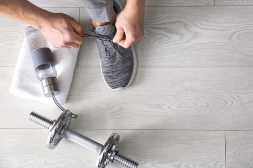 top view of man tying shoe laces in gym