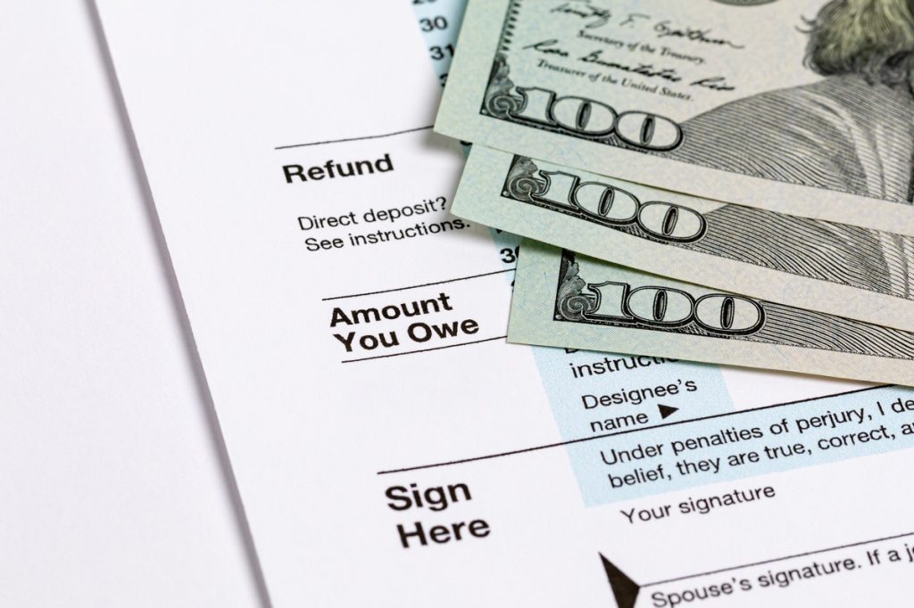 1040 individual income tax return form and three one hundred dollar bills