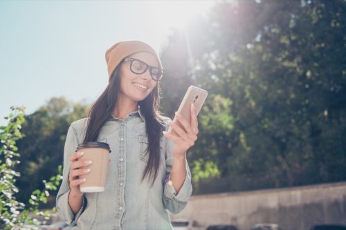 woman smiling while reading a message on her phone