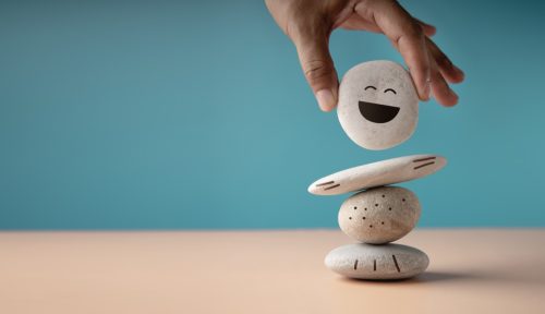 hand placing rock with smiley face on it onto a stack