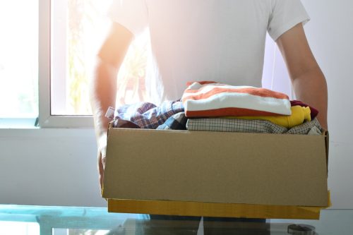man holding a box of clothes to be donated
