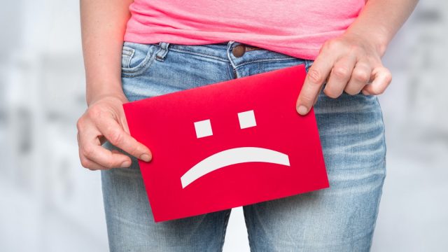 Woman with incontinence problem with sad smiley on paper - urinary incontinence concept
