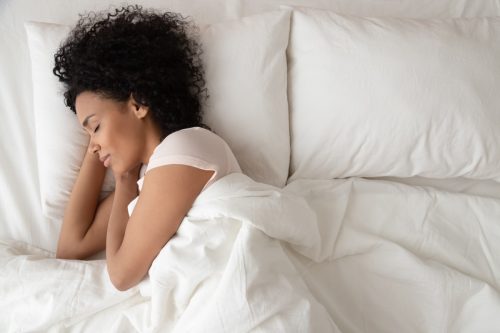 woman sleeping on her side on white linen