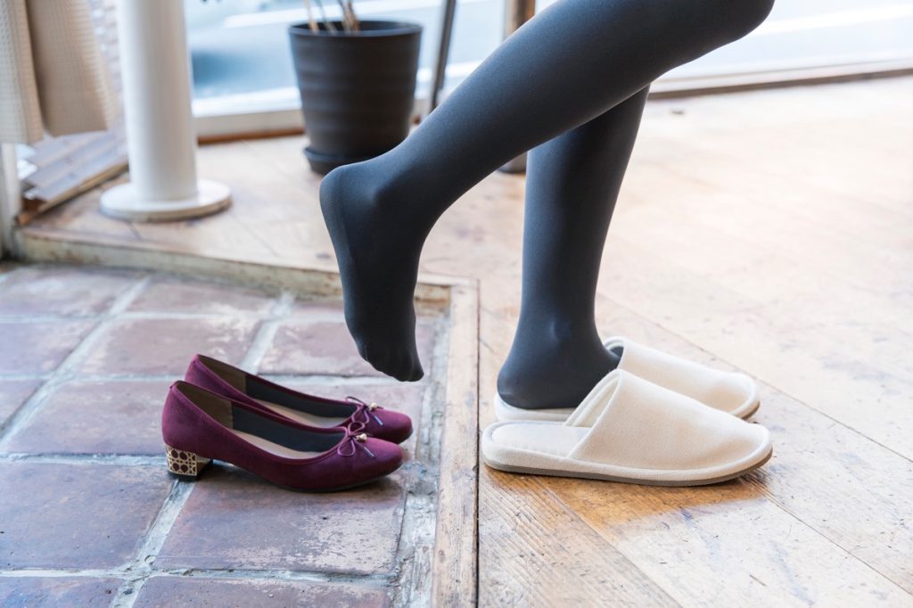 Close up on woman's feet in stockings stepping out of work shoes and into slippers