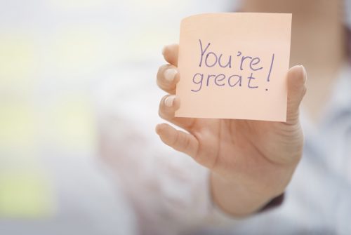 person participating in random acts of kindness by writing positive messages on sticky notes