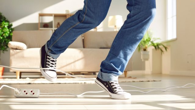 Legs of a person tripping over an extension cord in his living room