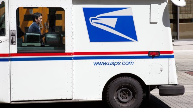 This image shows a USPS mail truck parked on the street near the Bellevue Square Mall in Washington State. You can see the mail delivery man standing on the far side of the truck.
