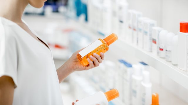 A woman holding two bottles of skincare products from the shelf at a store