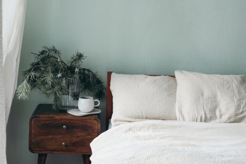 Close up of a bed white white sheets against light green walls