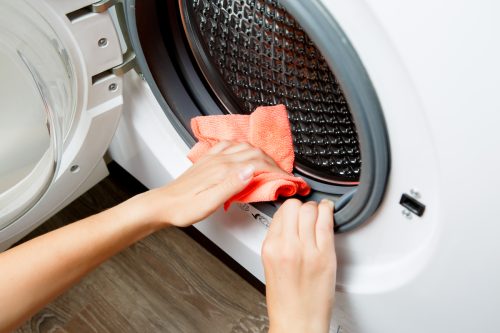 Photo of woman hands wiping cloth washing machine