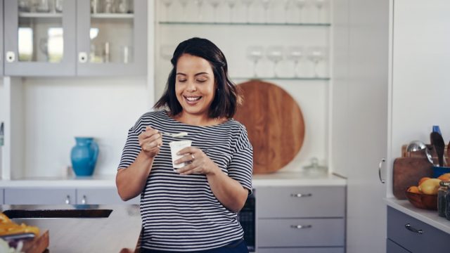 Shot of a young woman eating yogurt at home