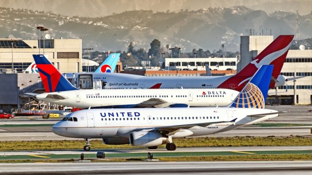 A United plane and Delta plane on the runway at a busy airport