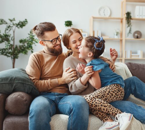 family laughing at funny jokes on the couch