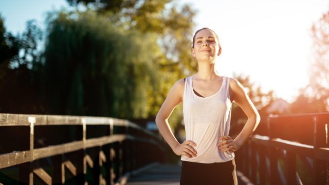 Sporty woman standing outside in the sunshine getting healthy