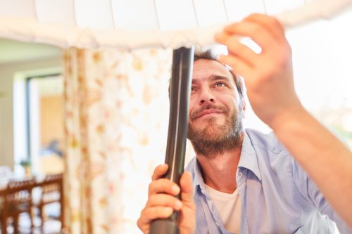 Man vacuuming a lamp shade