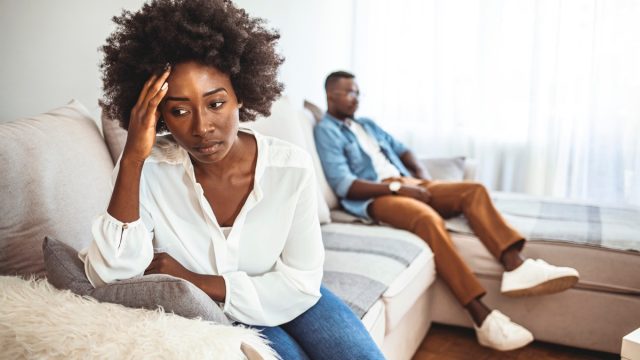 Unhappy Couple After an Argument in the Living Room at Home. Sad Pensive Young Girl Thinking of Relationships Problems Sitting on Sofa With Offended Boyfriend, Conflicts in Marriage,