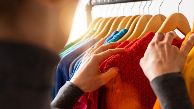 Fashion clothes hanging on clothing rack, in colorful rainbow colors