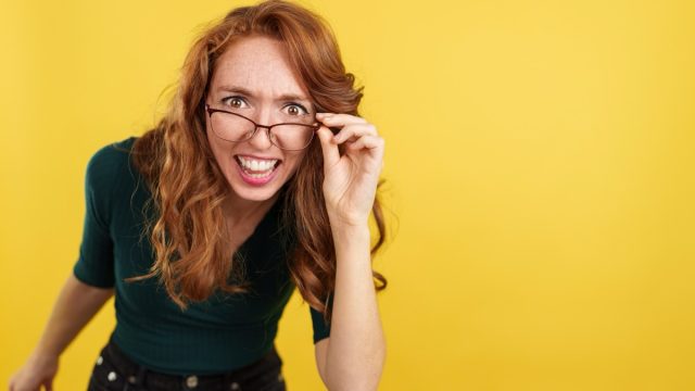 Redheaded woman with glasses looking at the camera with surprise