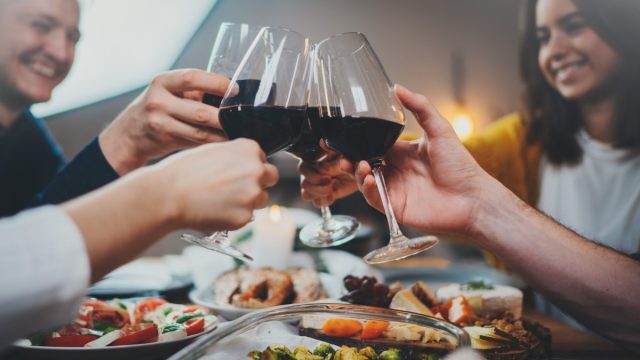 Group of happy friends celebrating and toasting with wine at party