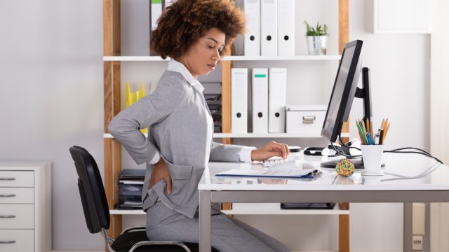 Young Businesswoman Suffering From Back Pain While Working In Office